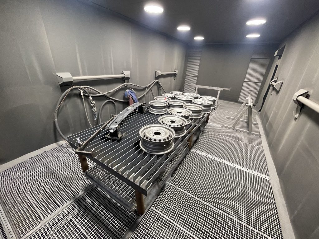 Felgi w kabinie śrutowniczej podczas oczyszczania powierzchni ze starej farby i korozji