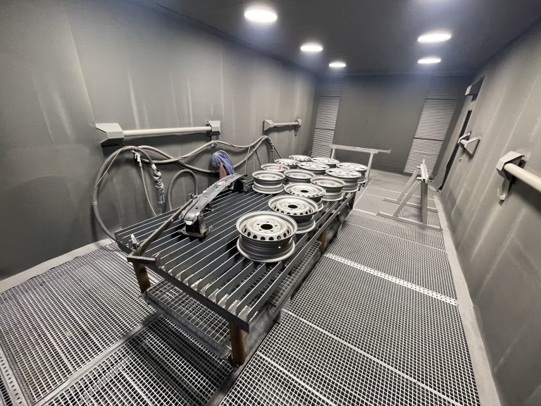 Felgi w kabinie śrutowniczej podczas oczyszczania powierzchni ze starej farby i korozji