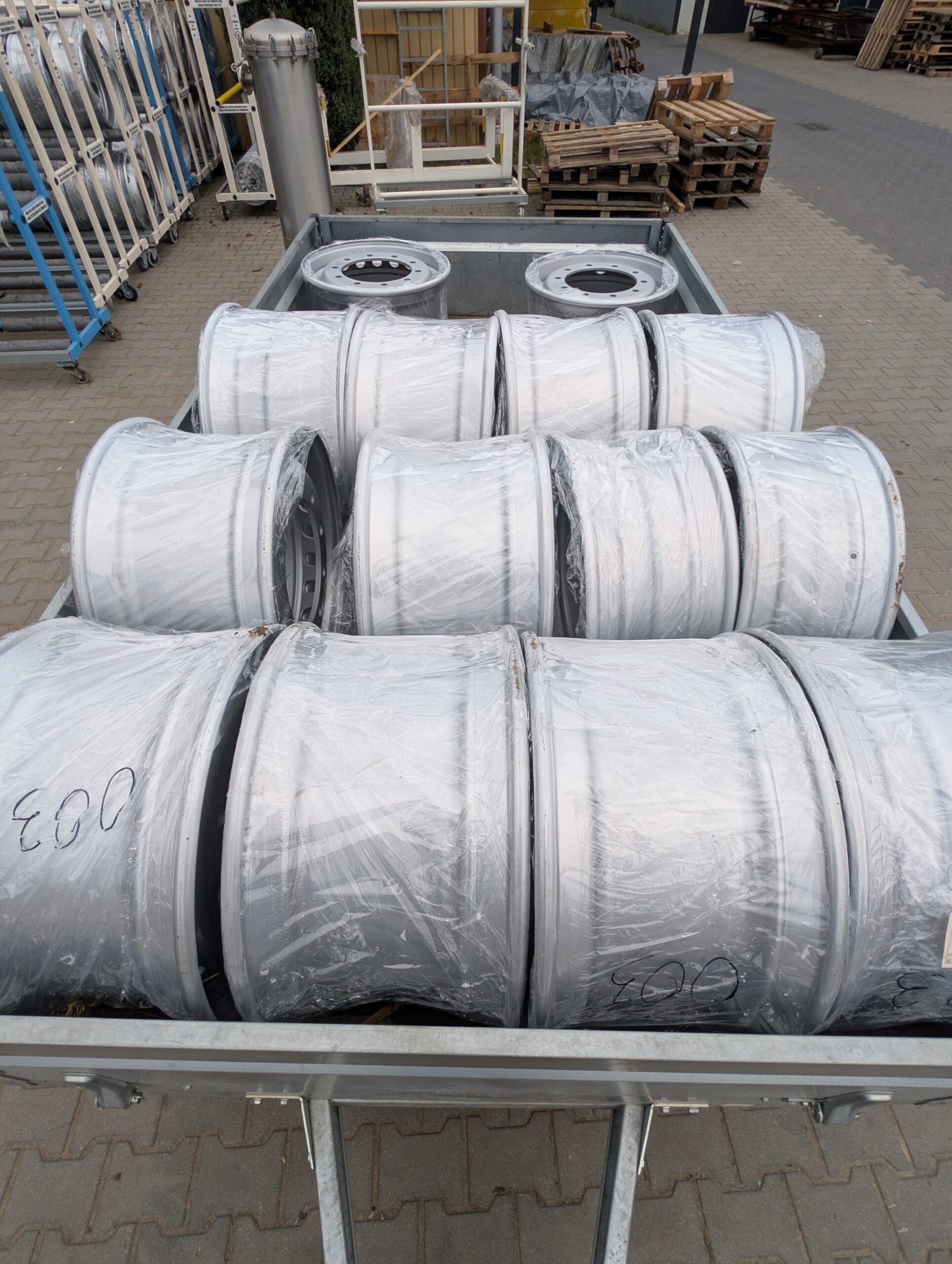 Odnowione felgi stalowe po renowacji, zapakowane w folię ochronną na palecie transportowej.